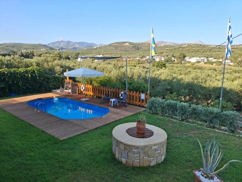a swimming pool in a yard with a table and an umbrella at Terra Solaris Guesthouse in Kissamos