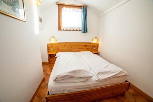 a small bedroom with a bed with white sheets at Residence Derby Club in Folgaria