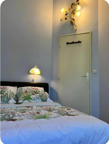 a bedroom with a bed with a door and a lamp at Belle chambre chez Zoa in Noisiel