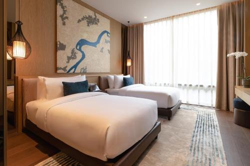 a hotel room with two beds and a large window at SOMA HOTEL Riverside in Phnom Penh