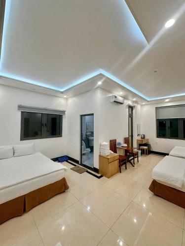 a bedroom with two beds and a table and chairs at Phụng Hoàng Vũ in Bạc Liêu