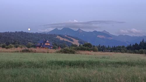 a house in a field with mountains in the background at Domek z Góralską Duszą Śleboda in Jurgów
