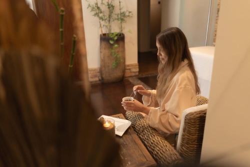 a woman sitting in a chair looking at her cell phone at Hotel Indigo La Paz Puerta Cortes by IHG in La Paz