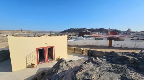 a small white building with a red door and some rocks at La Roca Self Catering & Accommodation in Lüderitz