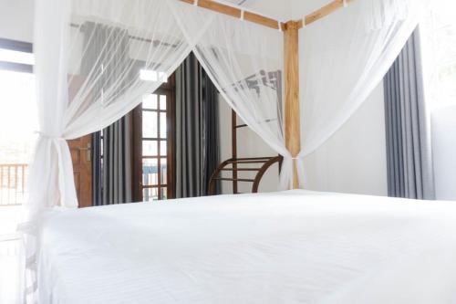 a bedroom with a white bed with a canopy at Slip Villa in Ahangama
