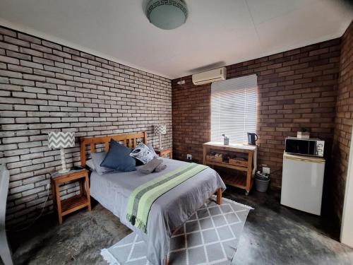 een slaapkamer met een bed en een bakstenen muur bij Oppieplaas in Alldays