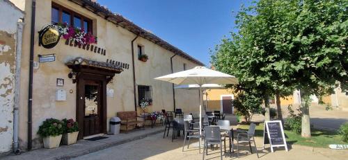 a restaurant with tables and chairs and an umbrella at Albergue Laganares - Exclusivo para peregrinos in San Nicolás del Real Camino