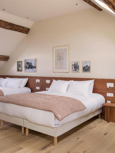 two beds in a bedroom with white walls at Alfred Hotels Beaune La Madeleine in Beaune