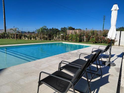 twee stoelen en een parasol naast een zwembad bij Correia Villa in Barcelos
