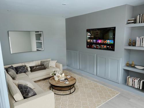 een woonkamer met een bank en een tv aan de muur bij Stunning Caterham 4 bedroom home in Kenley