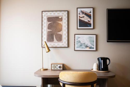 a desk with a chair and a tv on a wall at Home Hotel Havnekontoret in Bergen