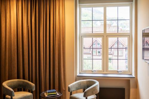 a room with two chairs and a window at Home Hotel Havnekontoret in Bergen