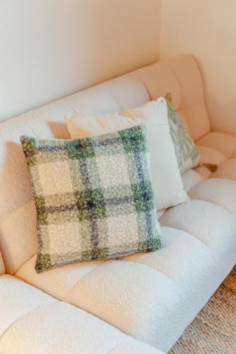 a white couch with a plaid pillow on it at Tenuta Alela in Figline Valdarno