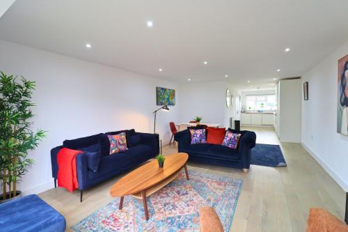 a living room with two blue couches and a table at London Mitcham Beautiful Three Bedroom House in Mitcham