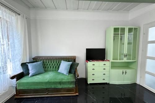 a living room with a green couch and a dresser at Nora Guest House - Happy Rentals in Nagygörbő