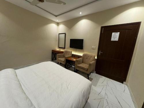 a bedroom with a bed and a desk and a television at The Luxe Nook in Islamabad