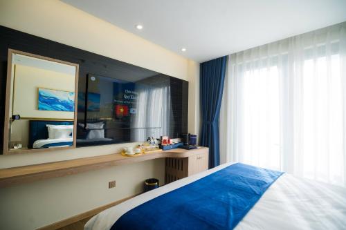 a bedroom with a blue bed and a mirror at Sandals Mimosa in Da Lat