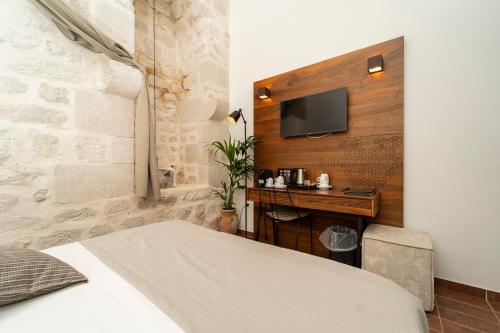 a bedroom with a bed and a desk and a tv at Heritage Hotel Maskovica Han in Pakoštane