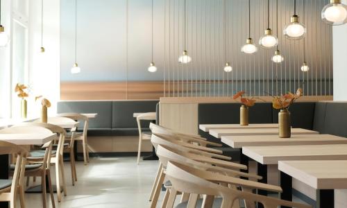 a restaurant with tables and chairs and pendant lights at Marienkron - Retreat & Health Resort in Mönchhof
