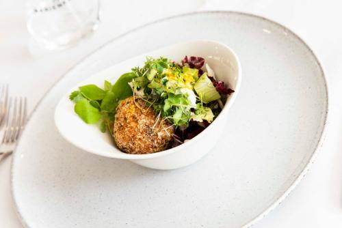 a white bowl of salad on a white plate at Marienkron - Retreat & Health Resort in Mönchhof