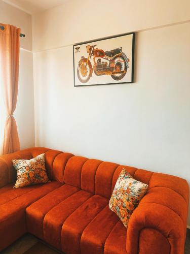 an orange couch in a living room with a motorcycle on the wall at Dala Luxury Homes in Kisumu
