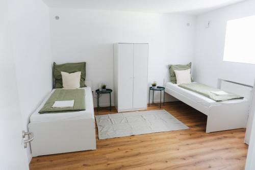 two beds in a white room with wooden floors at Ferienwohnung Zur Wieskapelle W3 - ideal für Monteure in Straubing