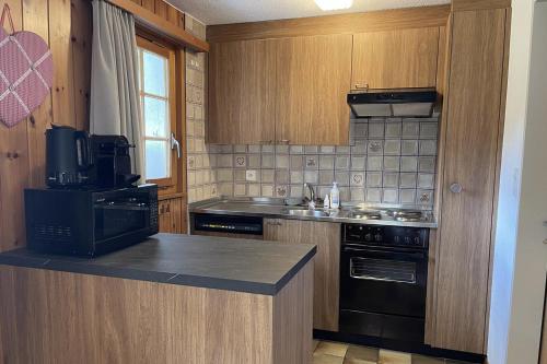 a kitchen with wooden cabinets and a black appliance at Chalet Woodland - Ferienwohnung mit Terrasse in Ritzingen