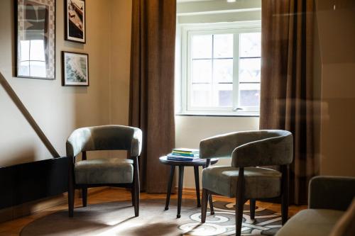 two chairs and a table in a room with a window at Home Hotel Havnekontoret in Bergen