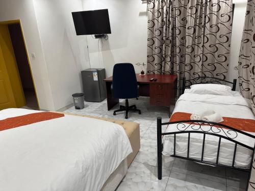 a bedroom with two beds and a desk with a computer at Pomona BB House in Harare