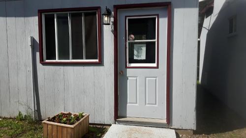 a white door and a window and a flower box at Fair Isle Motel & The Nest in Whycocomagh