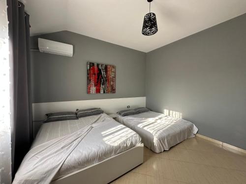 a bedroom with two beds and a painting on the wall at THE DOMI Apartments in Durrës