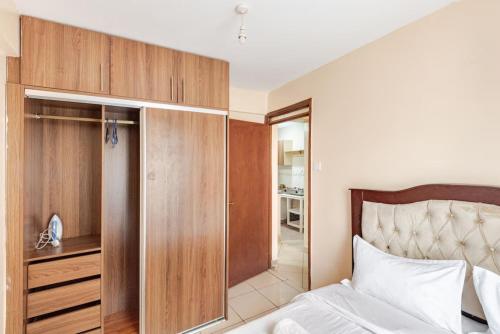 a bedroom with a bed and a wooden cabinet at NOVA Stays, Luxe 1BR apartment, South B in Nairobi
