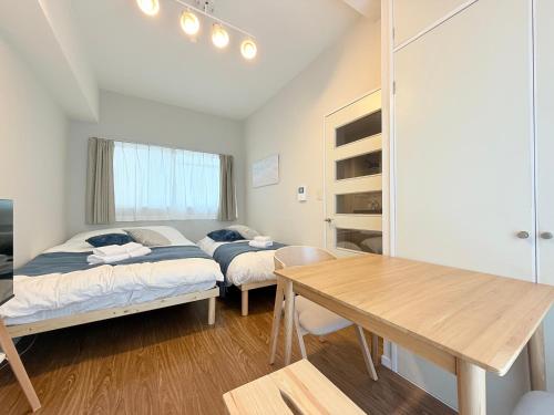 a bedroom with two beds and a wooden table at Cooee Chigasaki 406 in Chigasaki