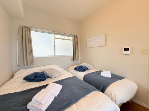 two beds in a room with a window at Cooee Chigasaki 406 in Chigasaki