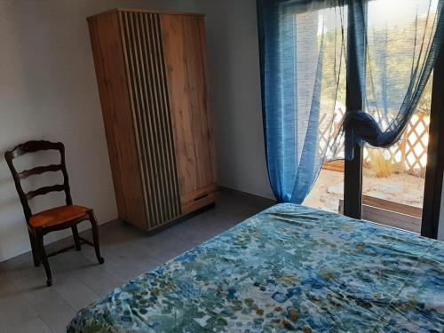 a bedroom with a bed and a chair and a window at Chez Louise in Arboussols