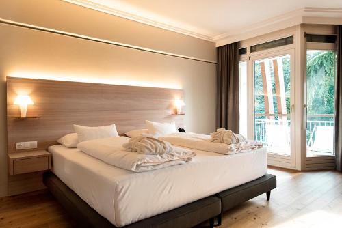 a bedroom with a large bed with white sheets at Marienkron - Retreat & Health Resort in Mönchhof