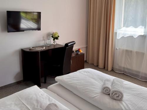 a hotel room with a desk and a bed with towels at HOTEL Garni PATRIOT in Trnava