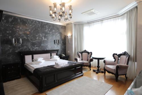 a bedroom with a bed and chairs and a chandelier at Villa Bijoux in Ploieşti