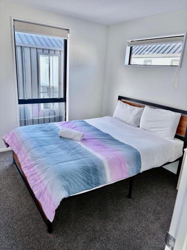 a bed in a white room with a large window at Modern 3BR Escape 3 Private Baths Rare Garage Perfect for Groups in Christchurch