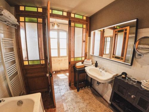 a bathroom with a sink and a tub and a mirror at Les Jardins de Baracane in Avignon