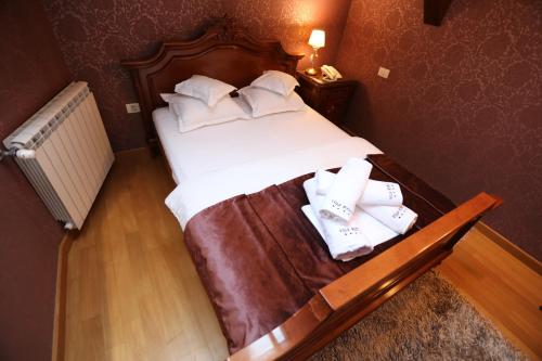 a bedroom with a bed with white sheets and towels at Villa Bijoux in Ploieşti