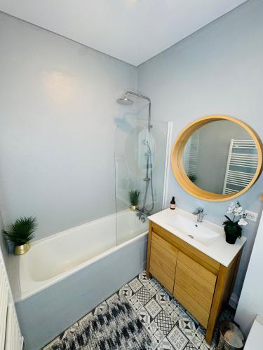 une salle de bain avec un lavabo, une baignoire et un miroir dans l'établissement Le cozy, Limoges, à Limoges