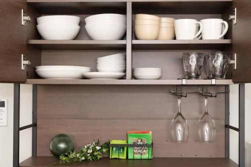 a kitchen cabinet with white dishes and wine glasses at Macchiato SHONAN-Vacation Stay- in Hiratsuka