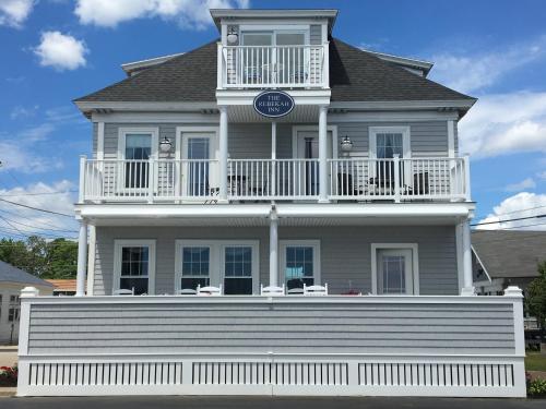 uma grande casa branca com uma varanda no topo em The Rebekah Inn em Old Orchard Beach