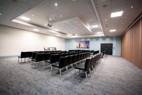 a room with rows of tables and chairs and a screen at Crowne Plaza Antwerpen by IHG in Antwerp