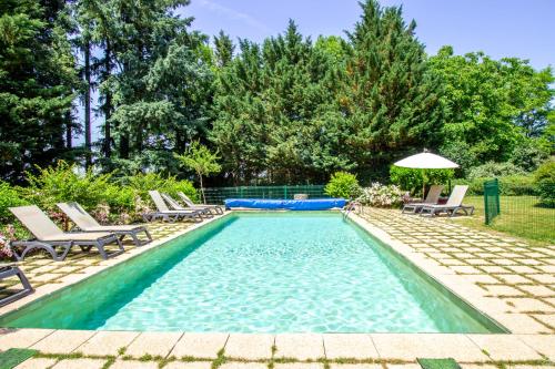 a swimming pool with chairs and an umbrella at Domaine du Puech Malou in Teillet