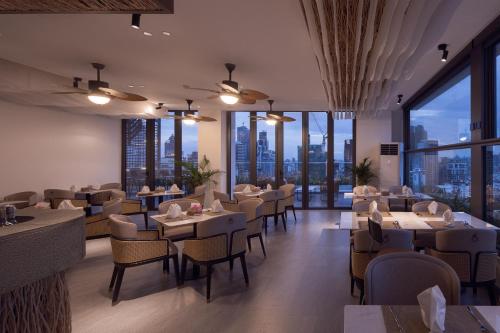 a restaurant with tables and chairs and large windows at Bassac Signature Hotel & Residence in Phnom Penh