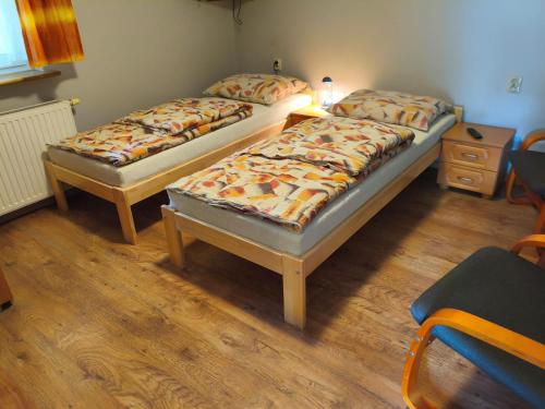 two twin beds in a room with wooden floors at Zajazd U Doktora in Lubrza