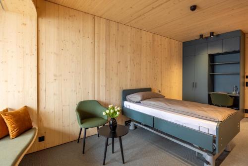 a bedroom with a bed and a chair and a table at Hotel Kurhaus am Sarnersee in Sarnen