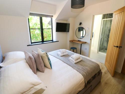 a bedroom with a large white bed with towels on it at Just A Cottage in Tenby